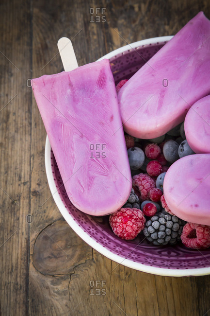 Homemade wild-berry ice lollies with raspberries- blueberries- red currants and blackberries in a bowl
