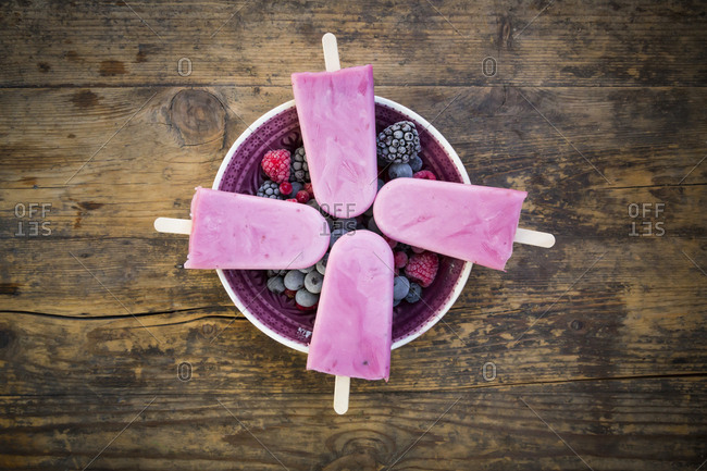 Homemade wild-berry ice lollies with raspberries- blueberries- red currants and blackberries in a bowl