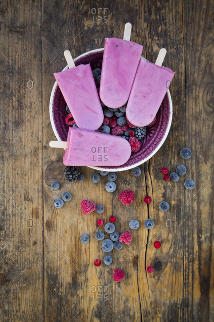 Homemade wild-berry ice lollies with raspberries- blueberries- red currants and blackberries in a bowl