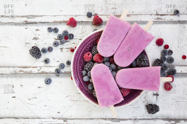 Homemade wild-berry ice lollies with raspberries- blueberries- red currants and blackberries in a bowl