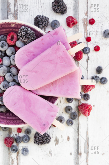 Homemade wild-berry ice lollies with raspberries- blueberries- red currants and blackberries in a bowl