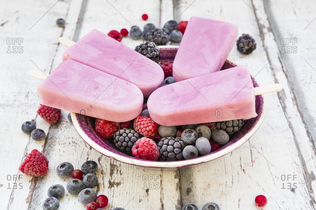 Homemade wild-berry ice lollies with raspberries- blueberries- red currants and blackberries in a bowl