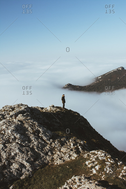 Man on rocky cliff in clouds