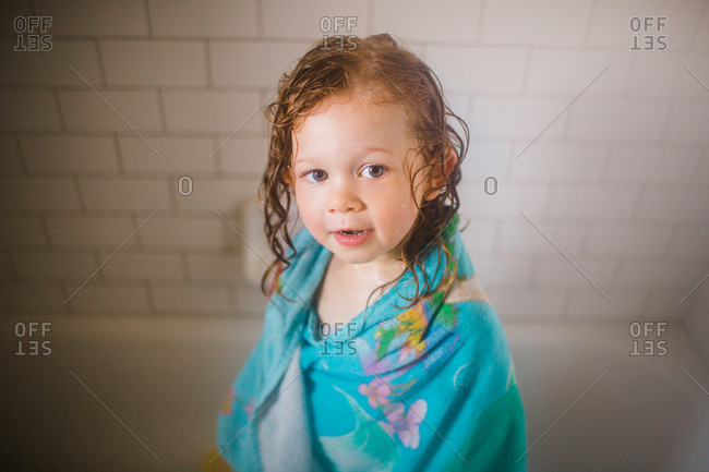 Toddler girl drying off after bath time