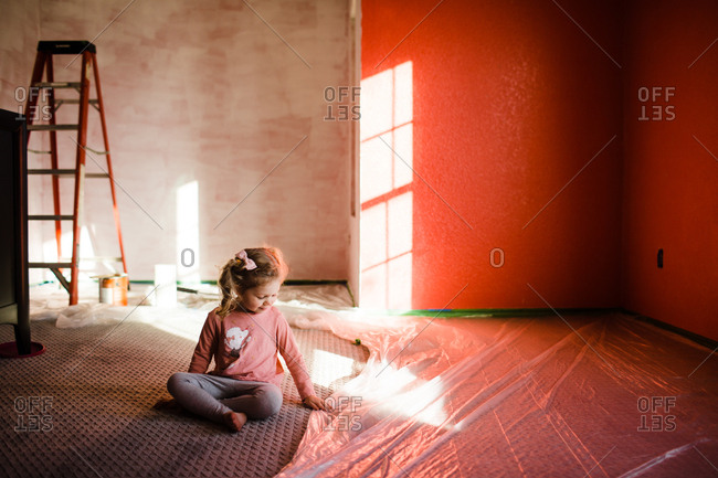 Little girl feels floor plastic in fresh painted bedroom
