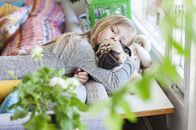 Girl hugging pug dog in living room