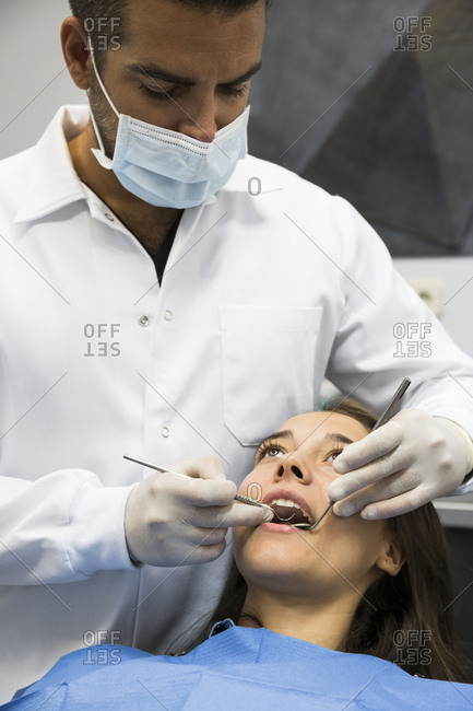 Dentist examining young female patient\'s teeth