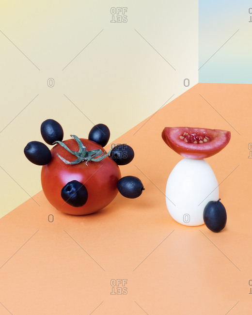 Surreal food presentation with tomatoes, olives, and an egg