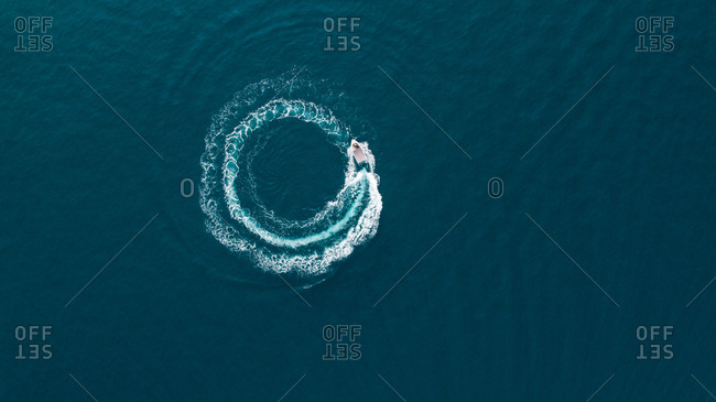 Aerial view of a boat driving in circle in the sea.
