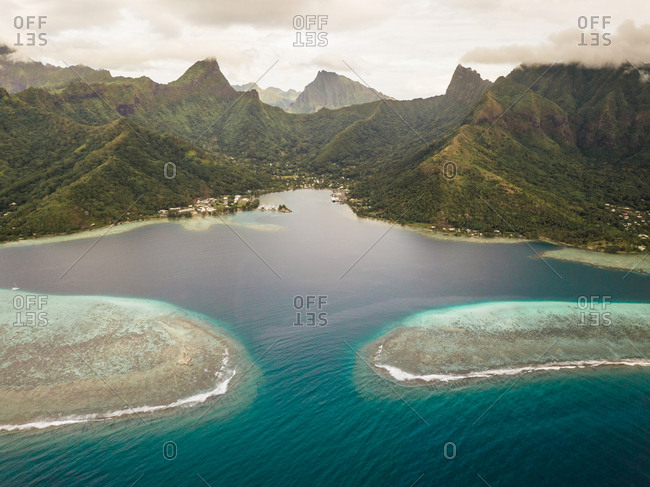 Aerial view of Moorea island and its shallow lagoon surrounded by the island's vertical mountains.