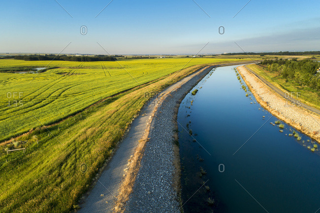 An irrigation canal with a path running alongside it and blue sky, East of Calgary; Alberta, Canada