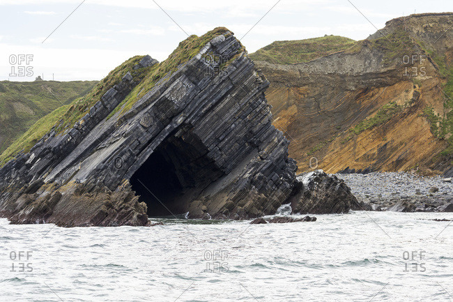 Rock Cave Eroded Out Of Cliff At Water's Edge With Cliffs In The Background; Ballybunion, County Kerry, Ireland