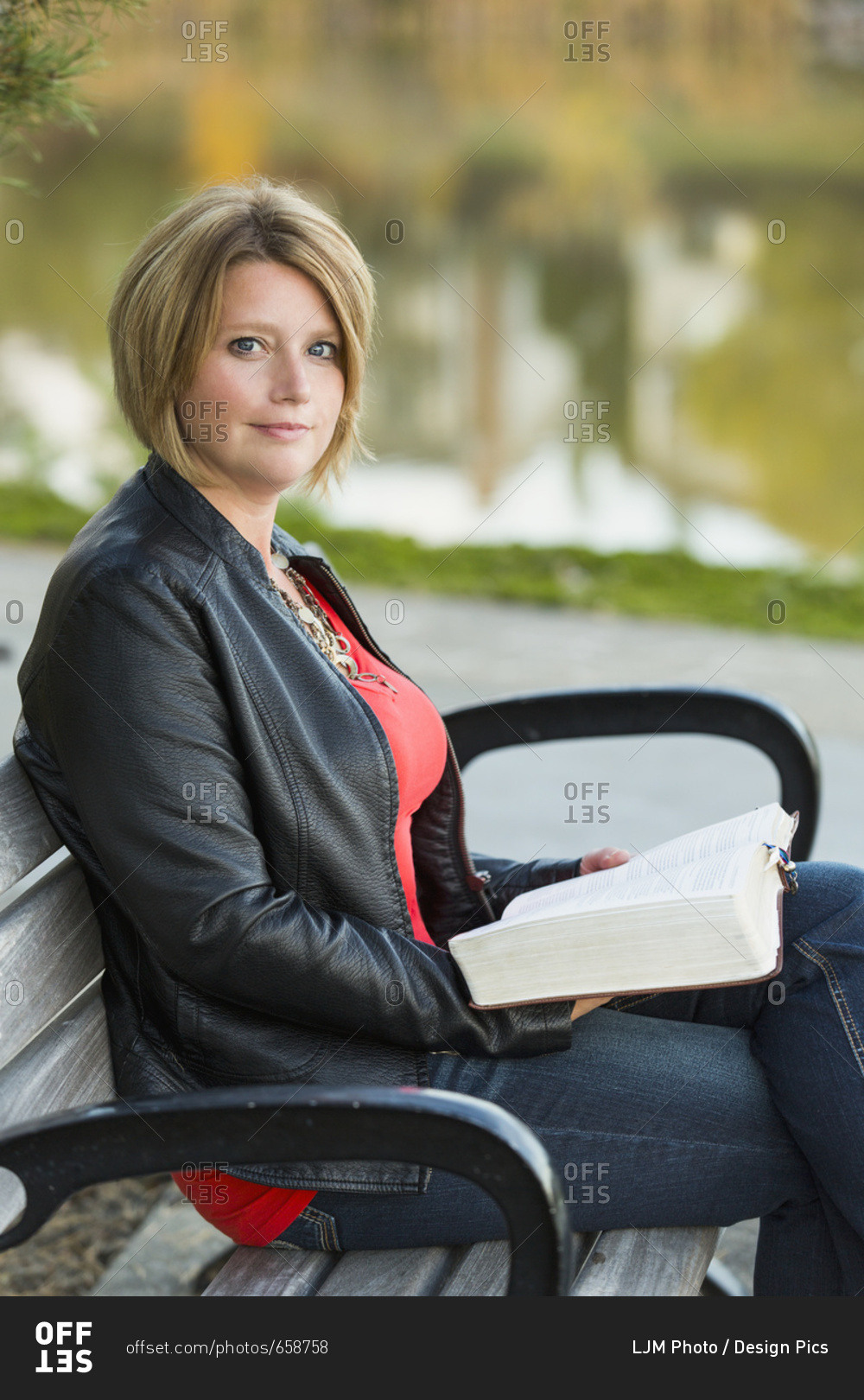 Mature Christian Woman Studying Her Bible In A City Park Setting Beside A Lake; Edmonton, Alberta, Canada