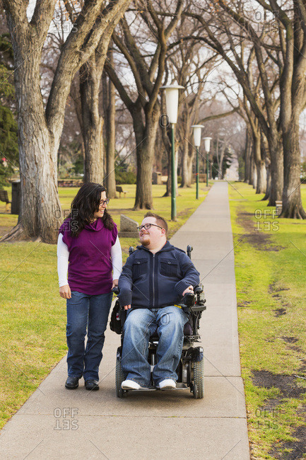 Disabled Husband Talking With His Wife While Walking In A Park In Autumn; Edmonton, Alberta, Canada