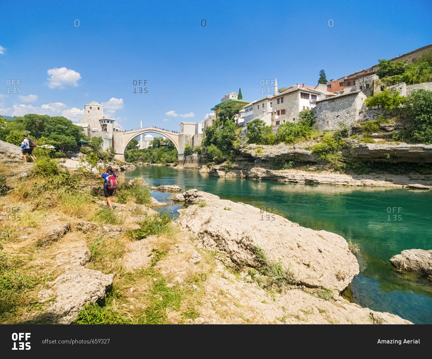 People on shore of Neretva river with Old Bridge in background, Mostar, Bosnia and Herzegovina.