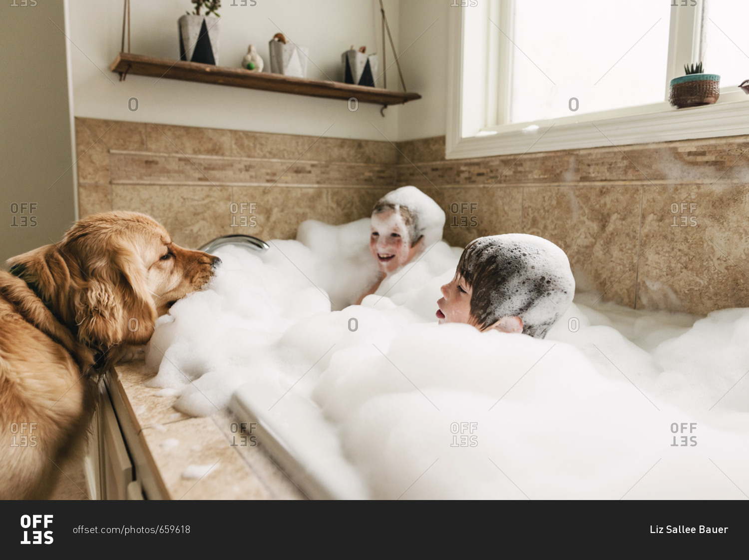 Dog sitting by bathtub while kids play in a bubble bath
