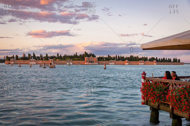 June 20, 2015: Couple in a Terrace Restaurant Facing the San Michele Cemetery Island of Venice at Sunset