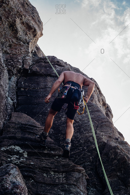 Rock climber using ropes to descend rock face