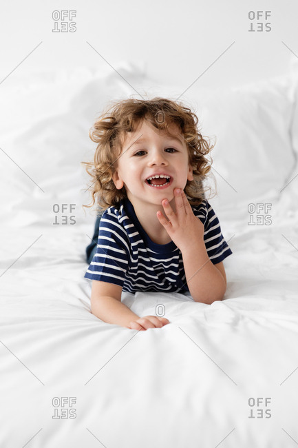 Little boy grinning to camera lying on bed
