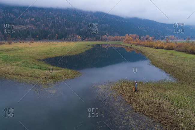 Vancouver, Canada - October 28, 2017: Male tourist standing with his dog near a lake at countryside