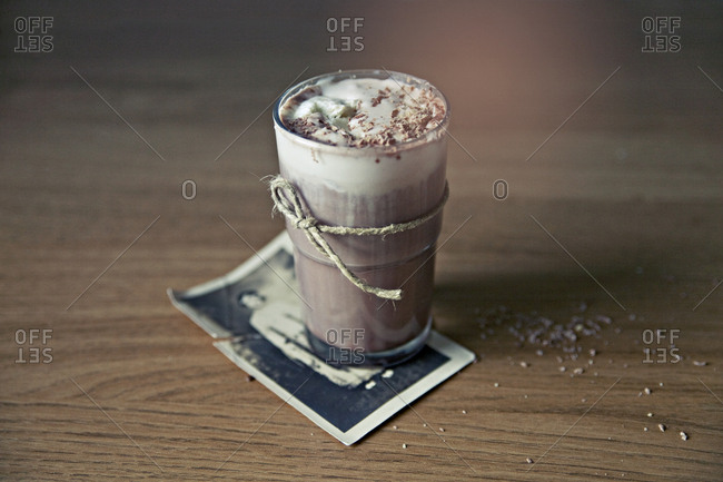 Creamy glass of hot chocolate with an old photograph as a coaster