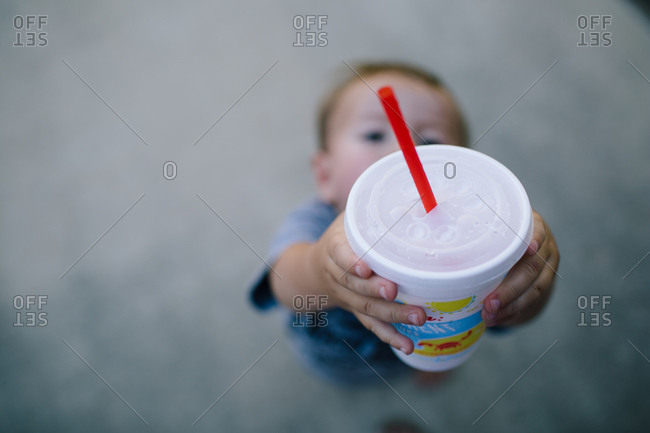 Toddler boy lifting drink in the air