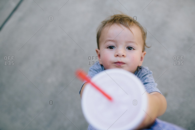 Toddler boy lifting beverage in the air