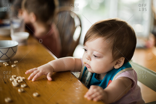 Small baby reaching for cereal while 