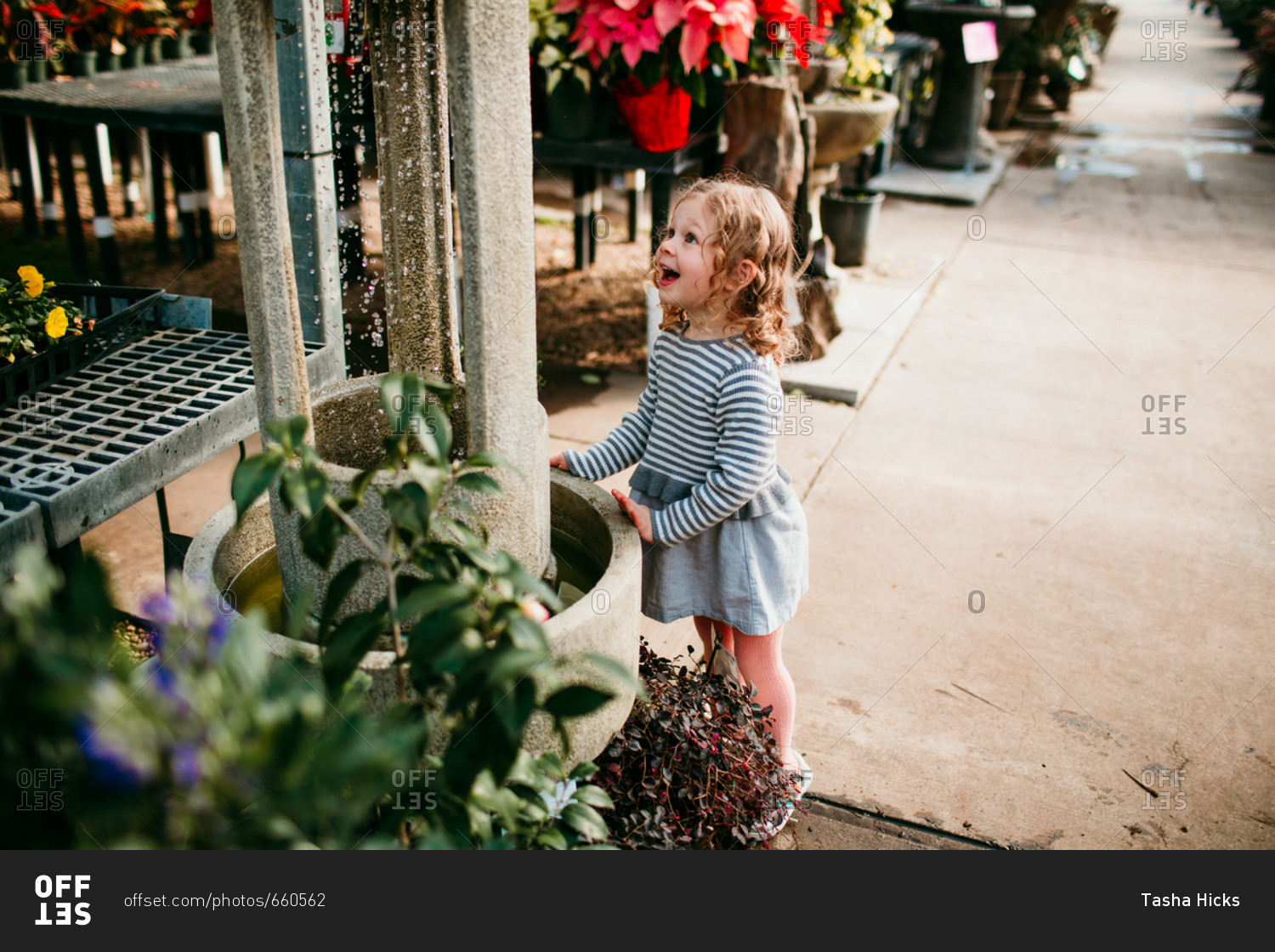 Little girl looking at water fountain in a garden center