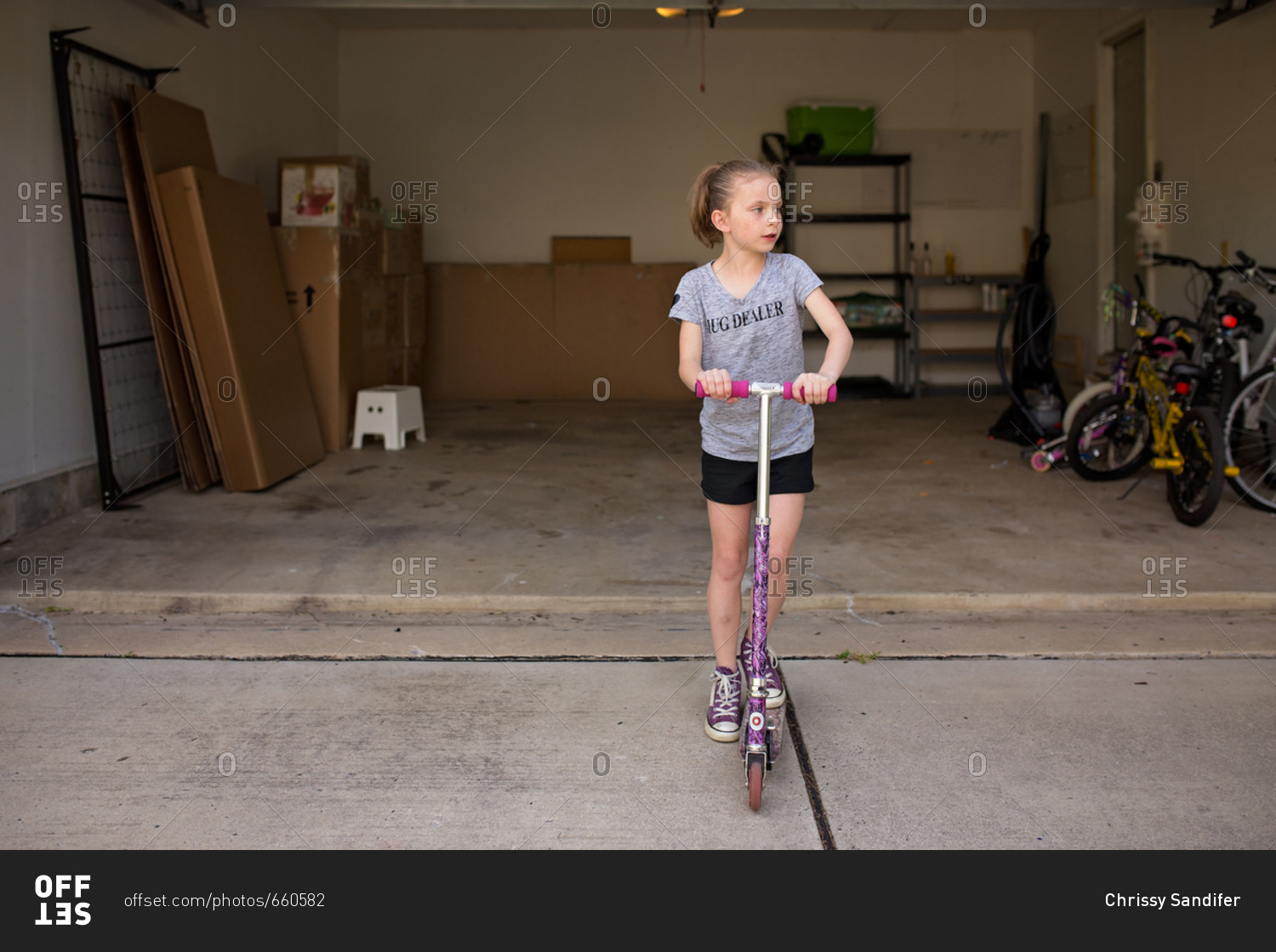 Girl riding scooter in front of moving boxes in a garage