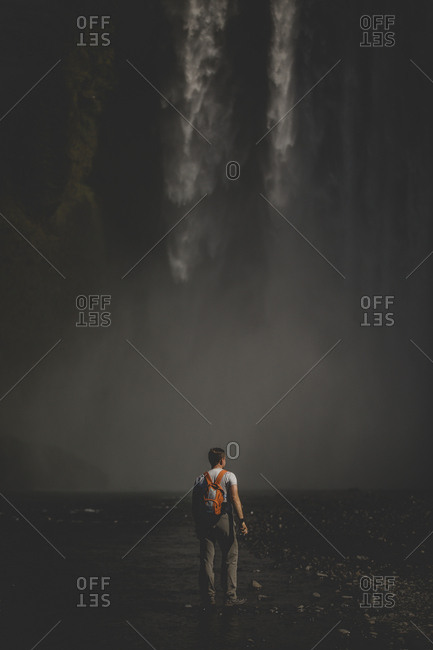 Traveler stopping at the foot of Skogafoss waterfalls in Iceland to take a photo