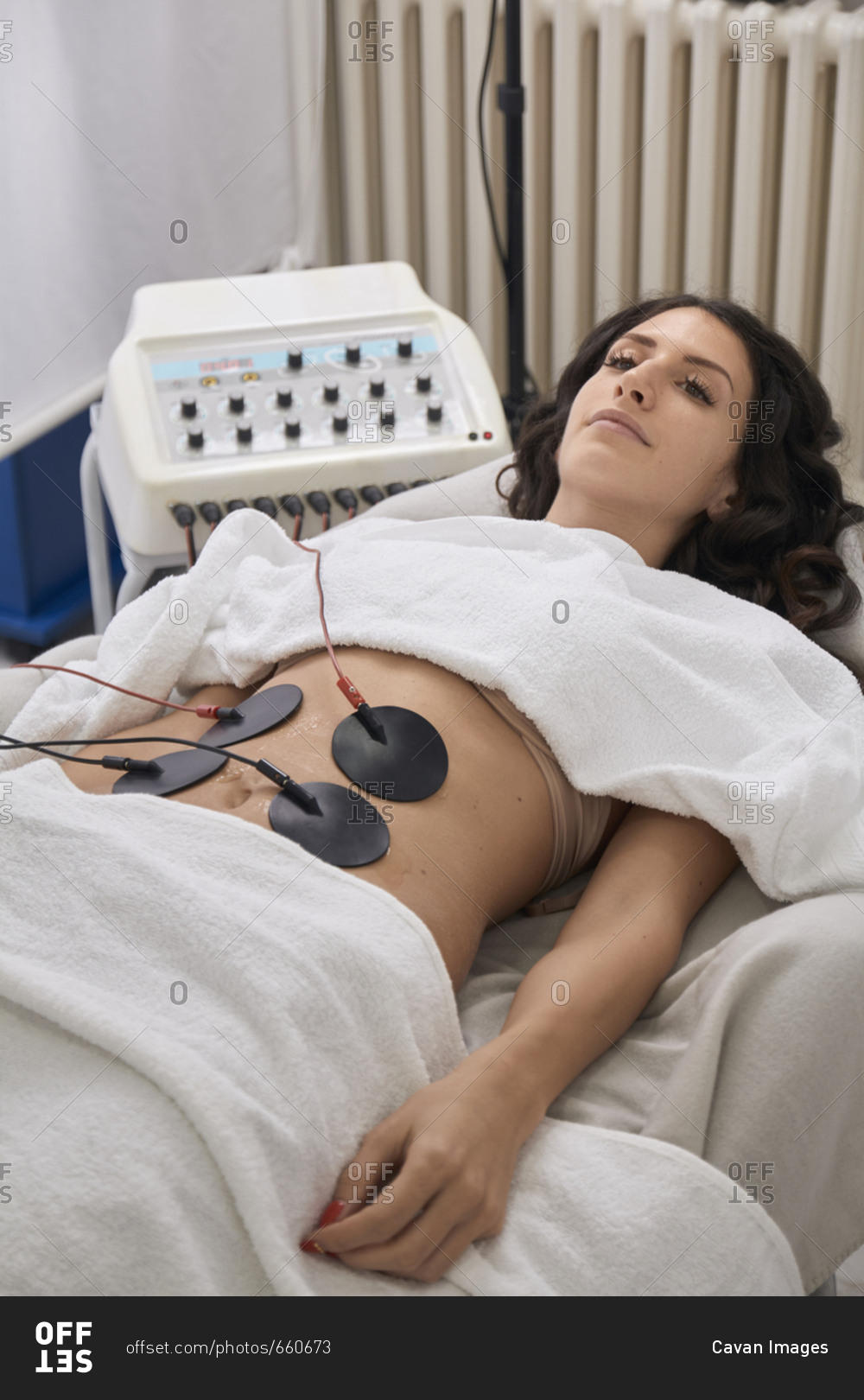 High angle view of patient having electrodes physical therapy while lying at medical clinic