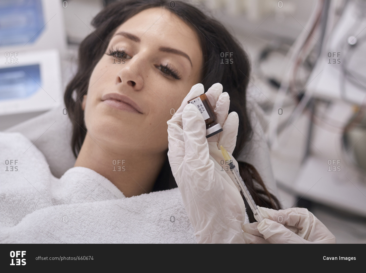 Cropped hands of female doctor filling liquid injection while patient lying at medical clinic