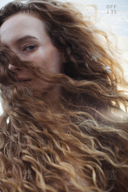 Portrait of a woman with long curly blond hair blowing in the wind stock  photo - OFFSET