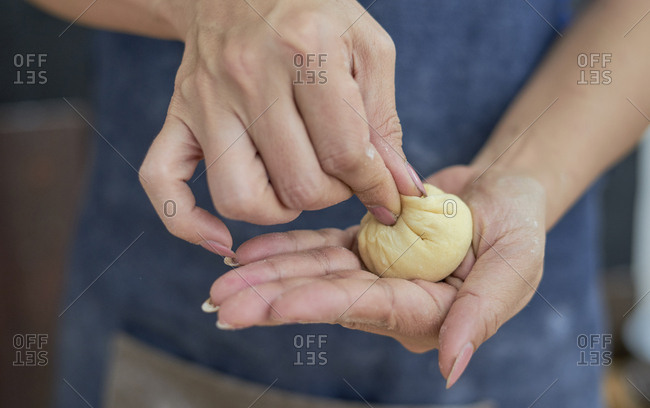 Midsection of woman making dough ball at home