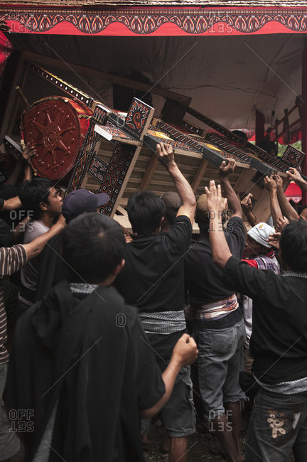 Rantepao, Sulawesi, Indonesia - September 3, 2013: Family lifting coffin in the air in celebration at a Toraja funeral