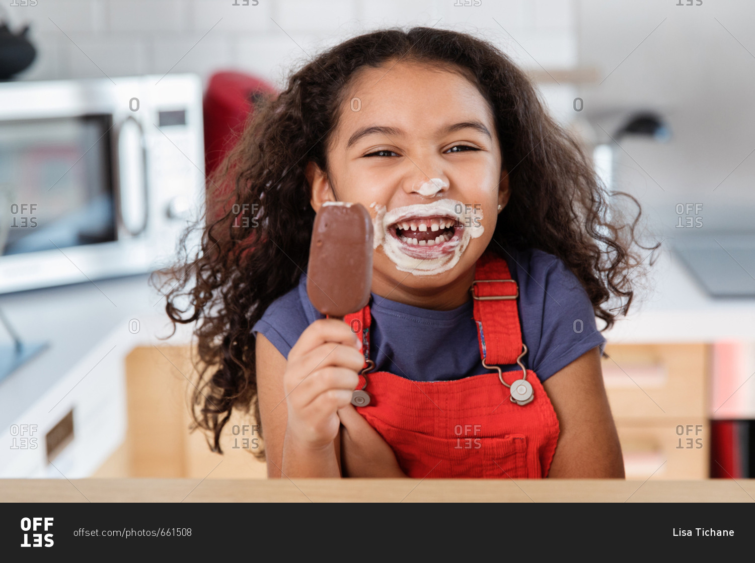 Little girl laughing with ice cream all over mouth and nose while