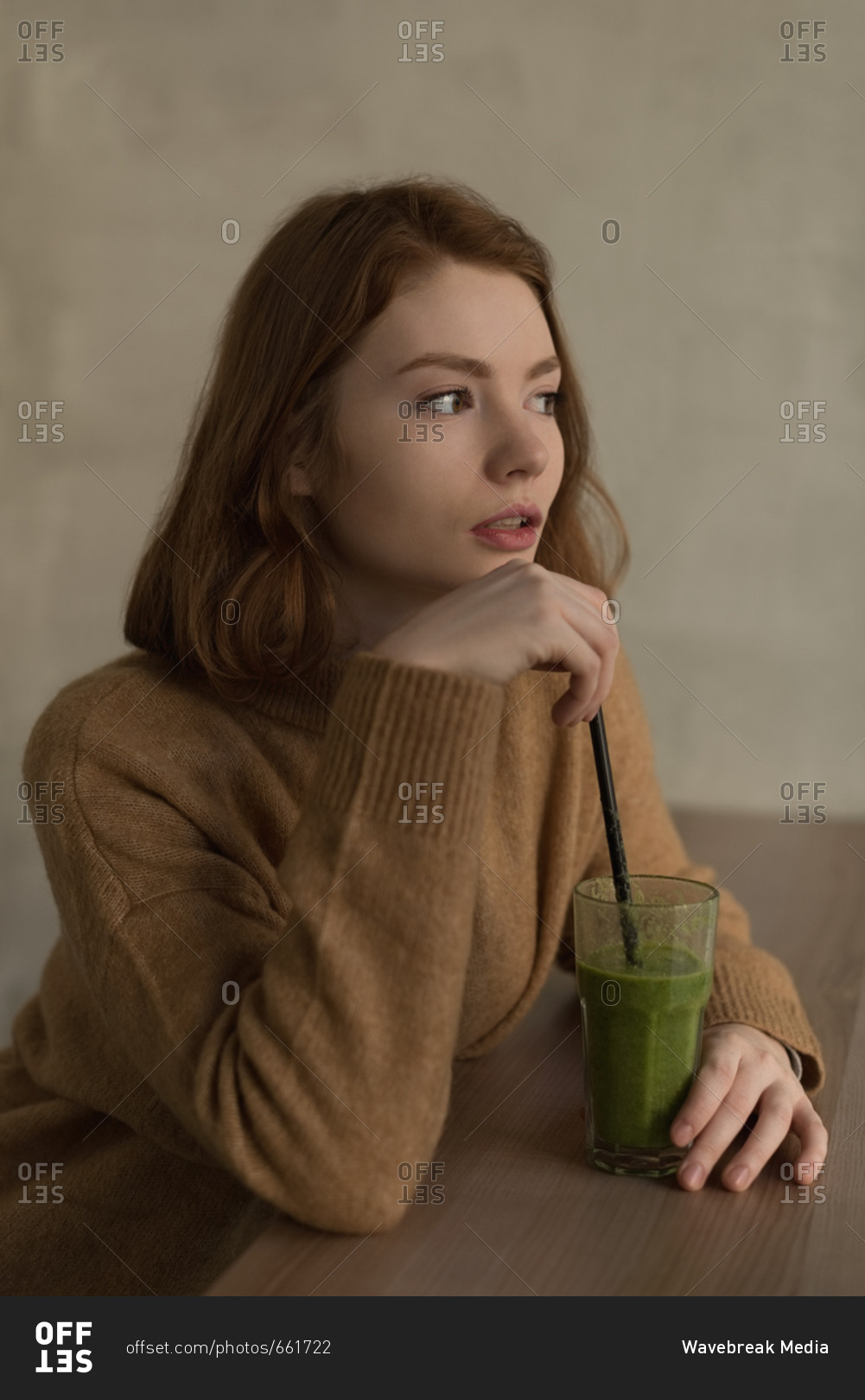Thoughtful woman having health shake drink in cafe