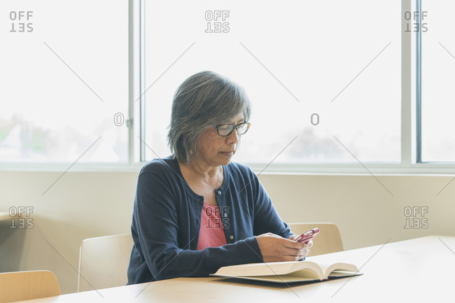 Filipino woman texting on cell phone in library