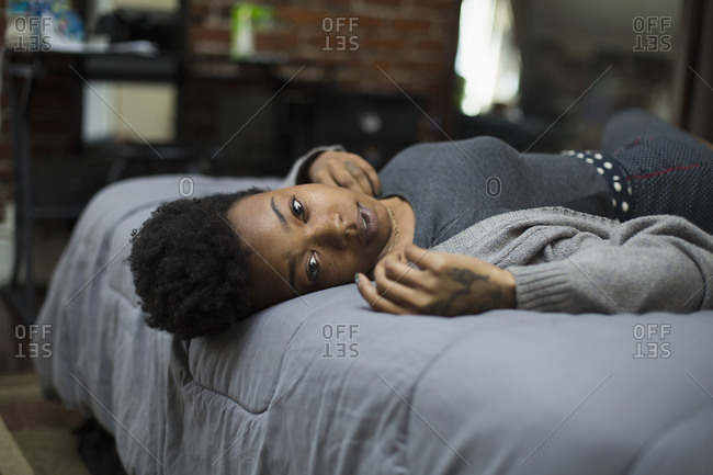 Portrait of young woman lying on bed at home