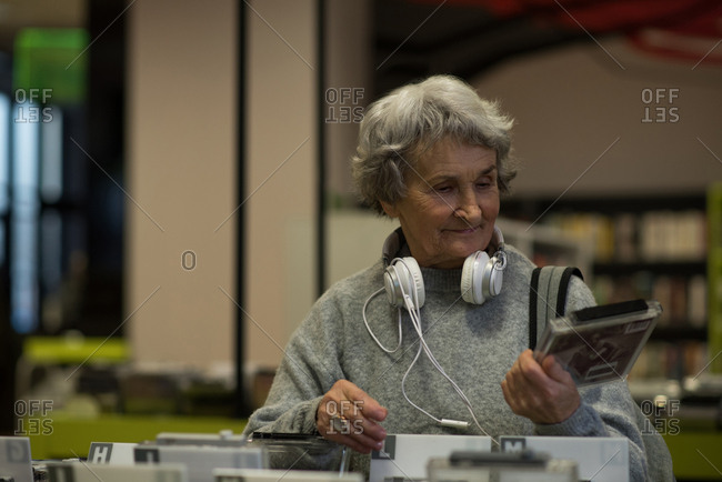 Senior woman choosing a dvd cassette in library