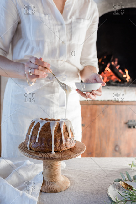 Person pouring icing on cake