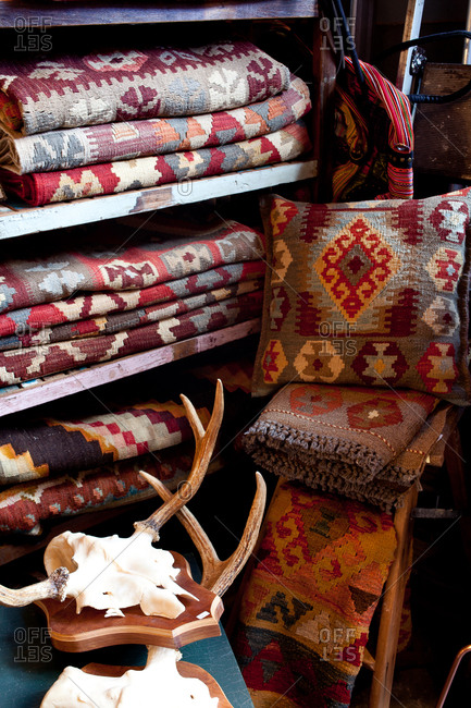 Woven rugs on a shelf beside animal skull and antlers