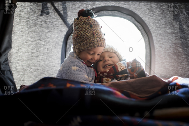 Smiling siblings sitting in roof tent