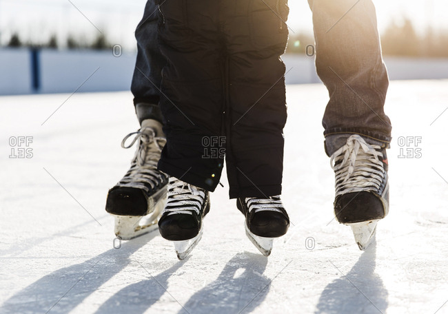Low section of mother with son ice-skating on snow