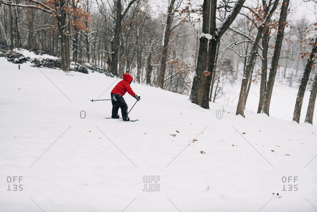 Happy toddler boy sliding down snow in the mountains stock photo - OFFSET