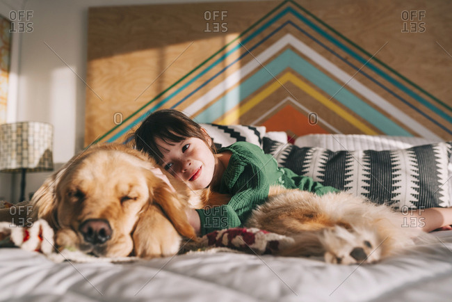 Young girl lovingly hugging pet Golden Retriever on the bed