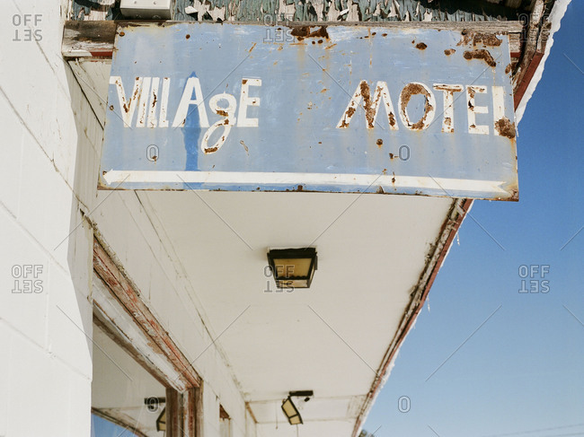 Weathered sign hanging from abandoned motel awning