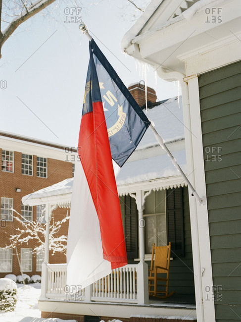 State flag of North Carolina displayed on house on a snowy day