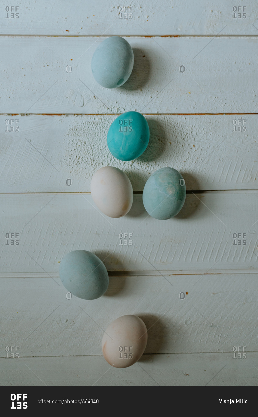 Pastel blue and white Easter eggs on a white wooden background